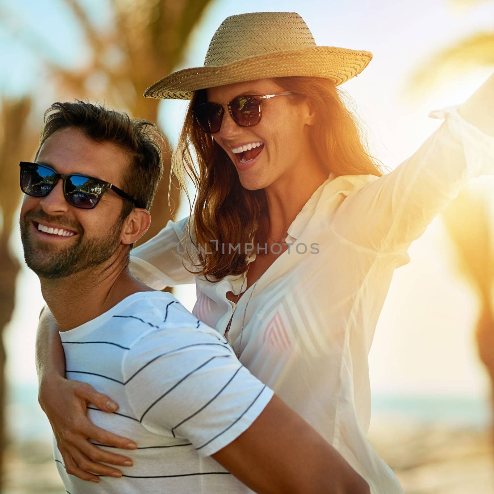 Live, love, and play. a happy young couple enjoying a piggyback ride at on a summers day outdoors. by YuriArcurs