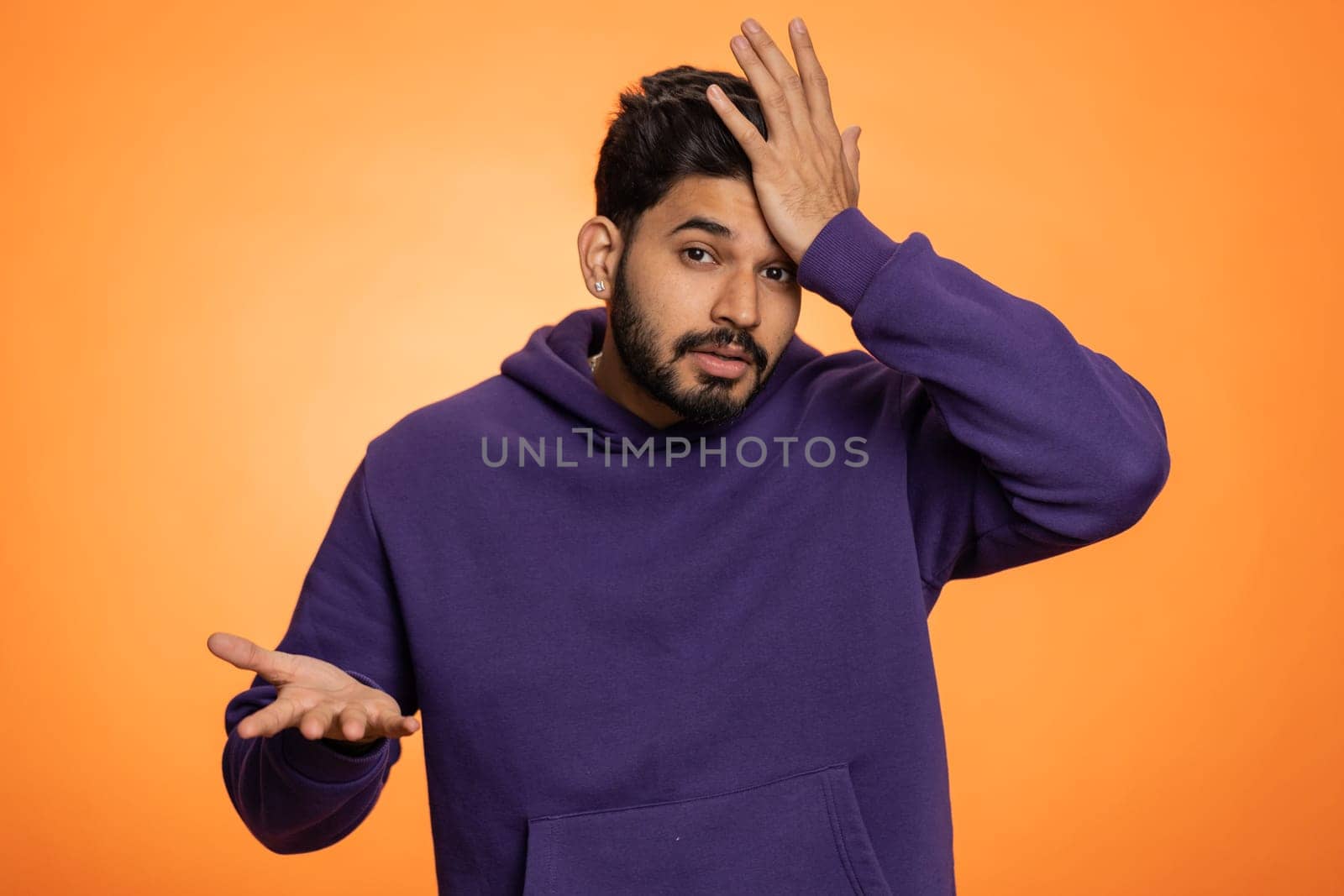 Face palm. Shame on you. Upset surprised young indian man making face palm gesture, loses, feeling bored, disappointed in result, bad news. Handsome hindu guy isolated on orange background, indoors