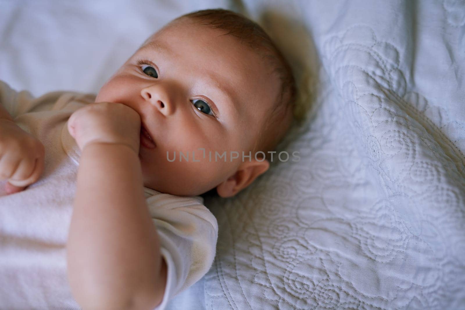 Cuteness overload. an adorable baby boy lying down on a bed at home. by YuriArcurs