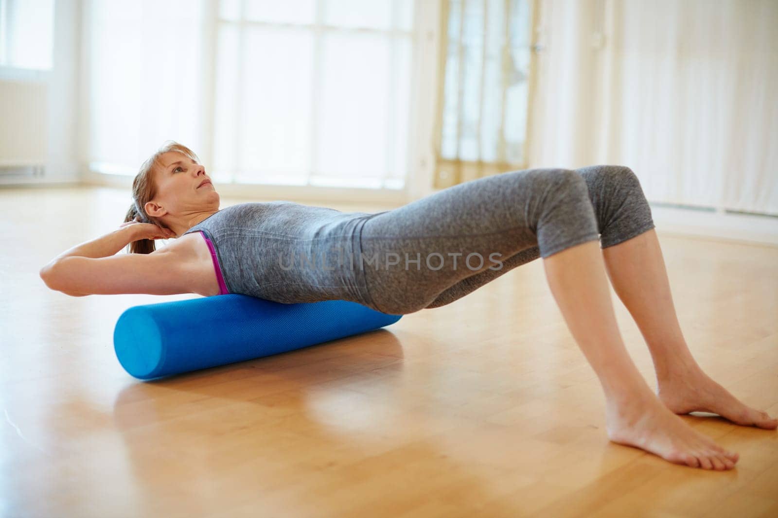 Yoga keeps her super flexible. a woman doing roller foam exercises during a yoga workout