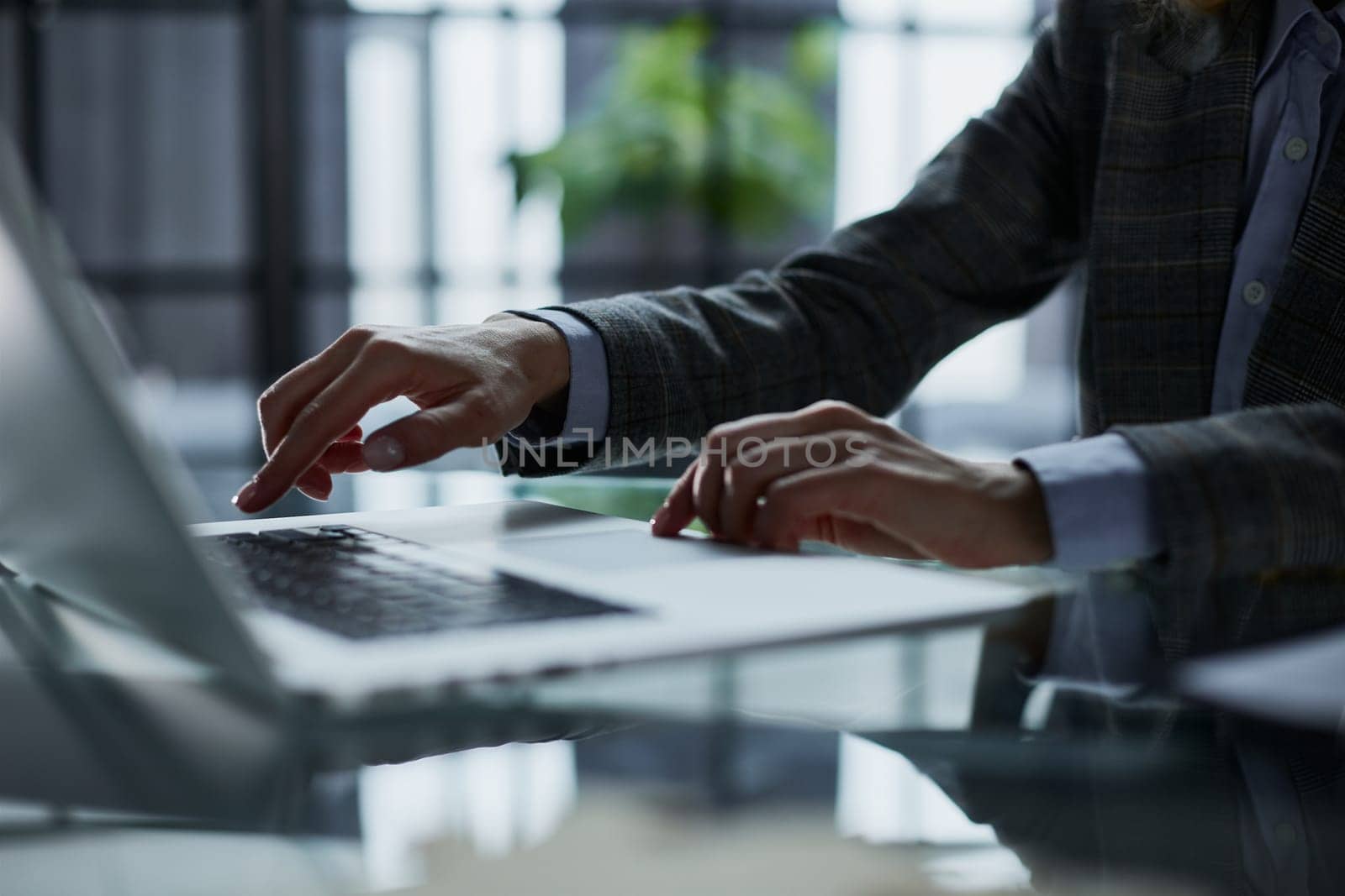 man's hands typing on laptop keyboard in interior