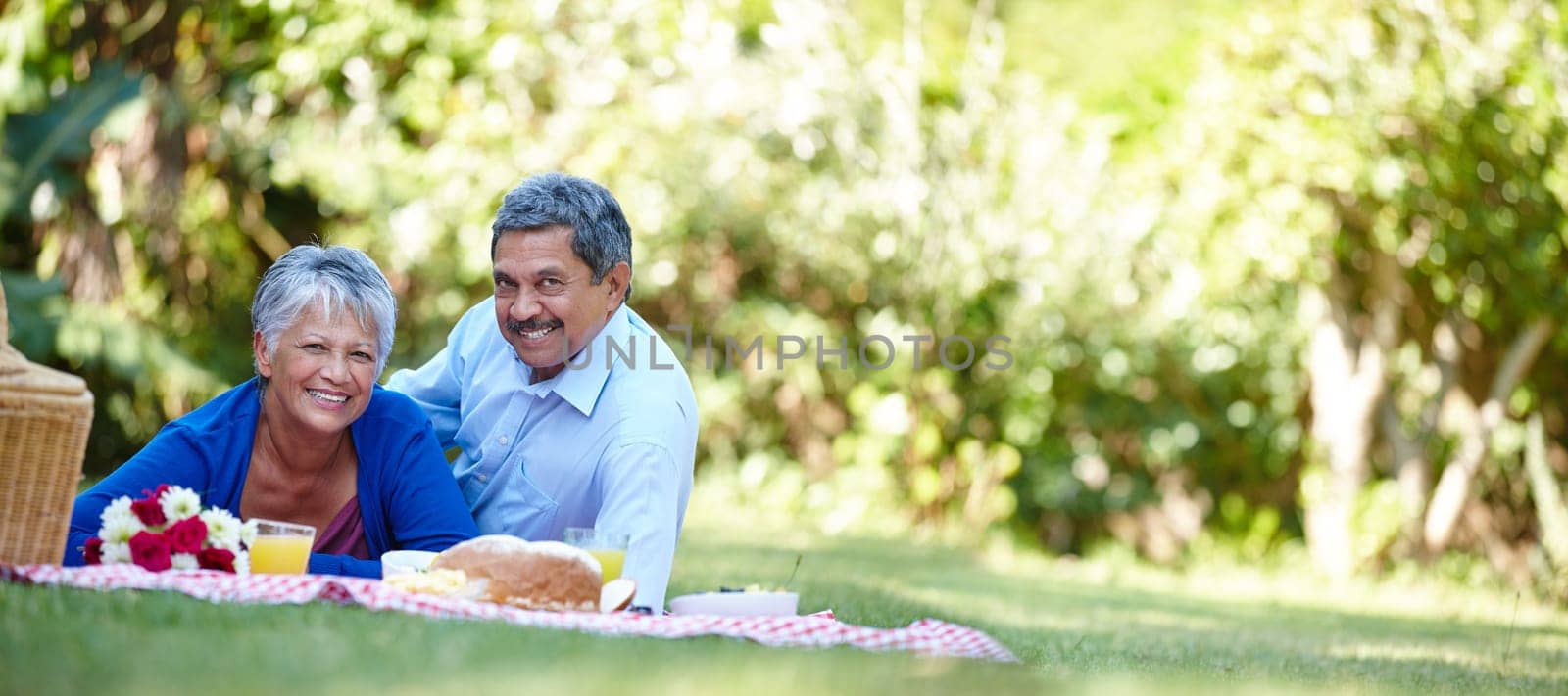 Enjoying a romantic retirement. a loving senior couple enjoying a picnic together outdoors. by YuriArcurs