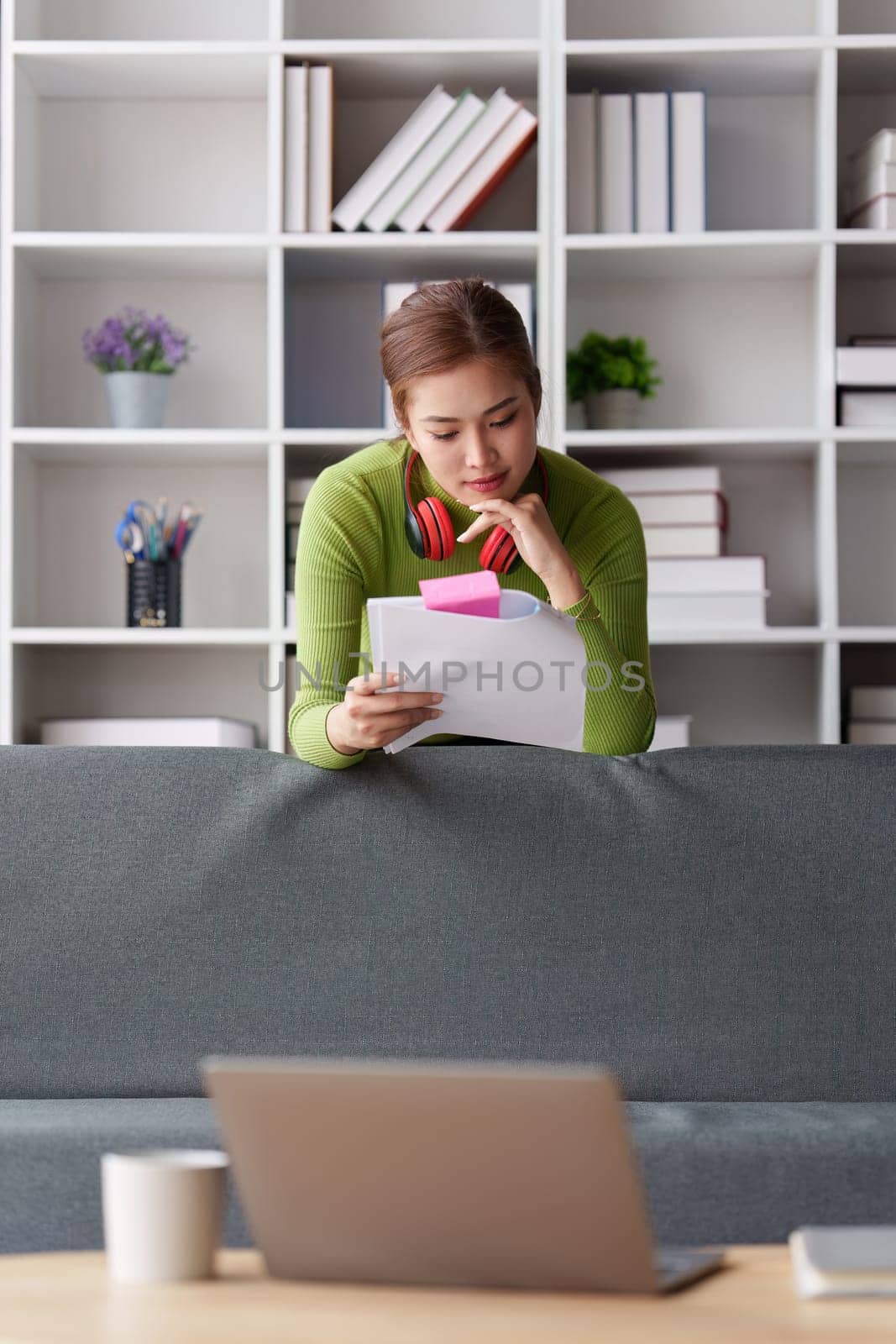 Woman sits on sofa at home, studying and analyze house bills and submitting tax forms..