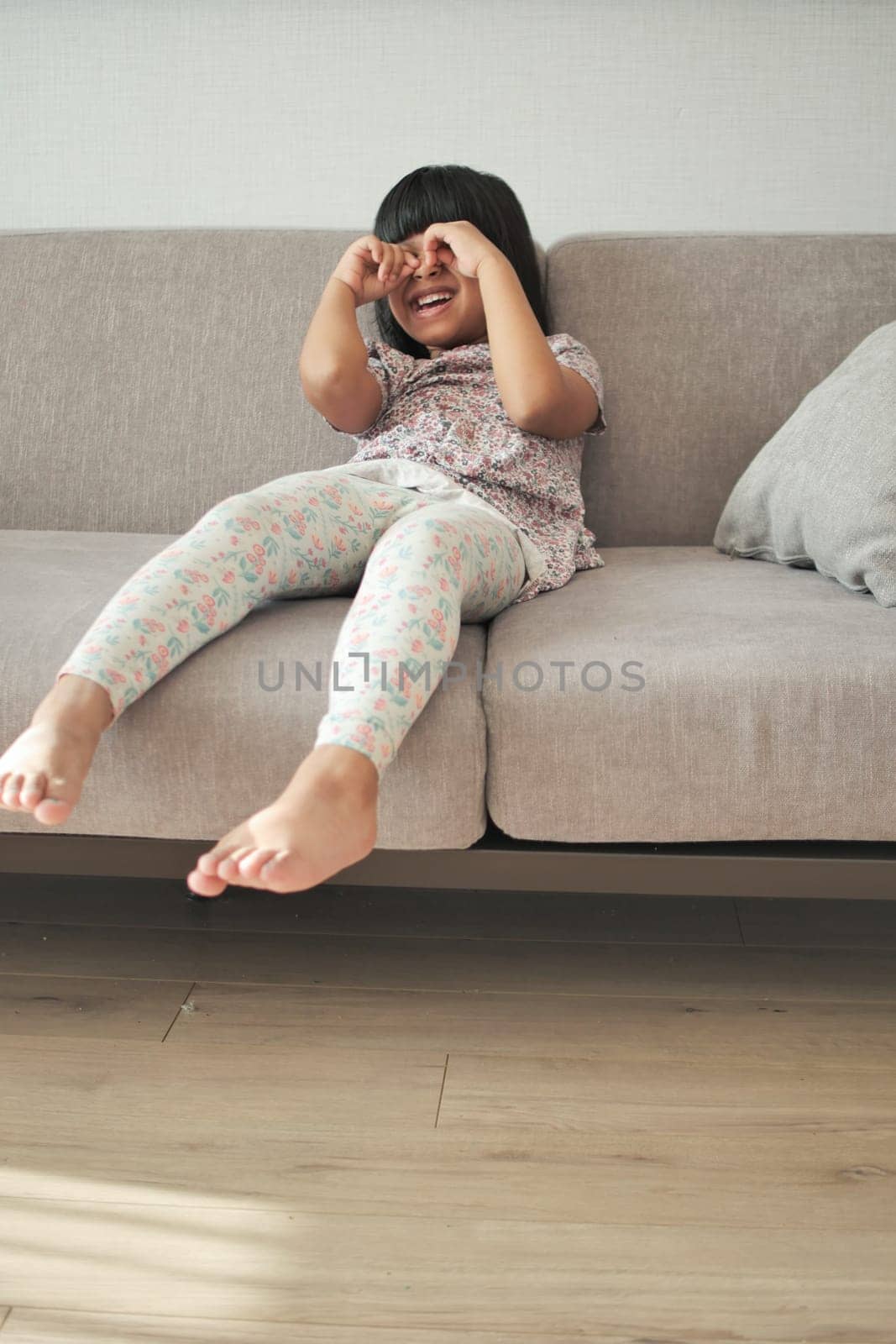 a upset child girl cover her face with hand sitting on sofa by towfiq007
