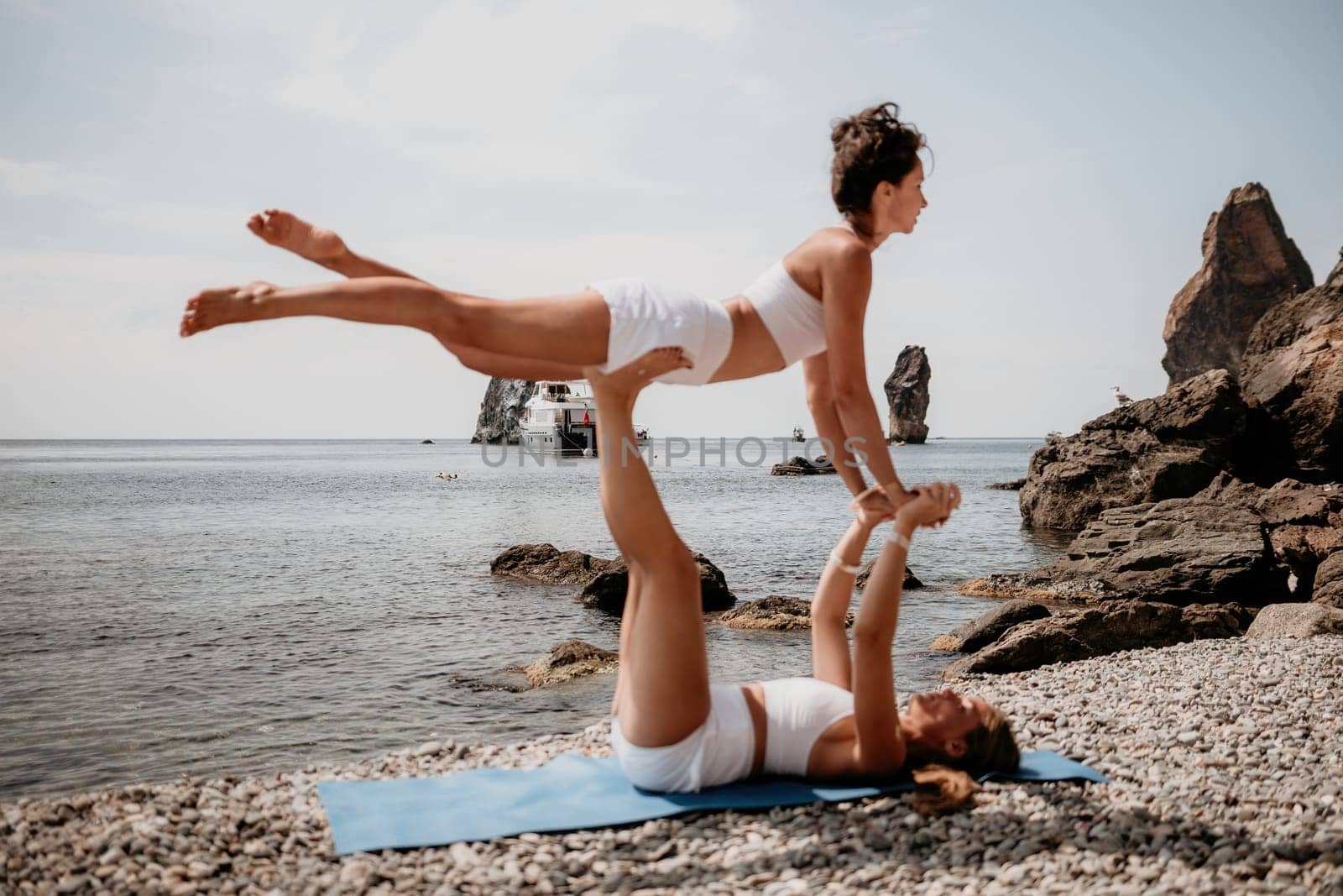 Woman sea yoga. Back view of free calm happy satisfied woman with long hair standing on top rock with yoga position against of sky by the sea. Healthy lifestyle outdoors in nature, fitness concept.