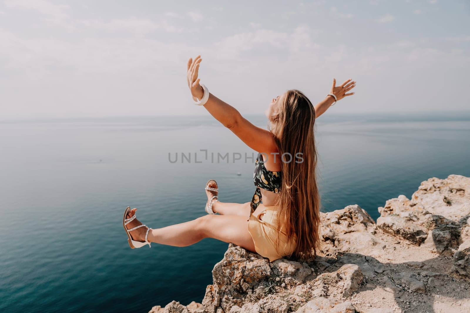 Woman travel sea. Happy tourist taking picture outdoors for memories. Woman traveler looks at the edge of the cliff on the sea bay of mountains, sharing travel adventure journey.