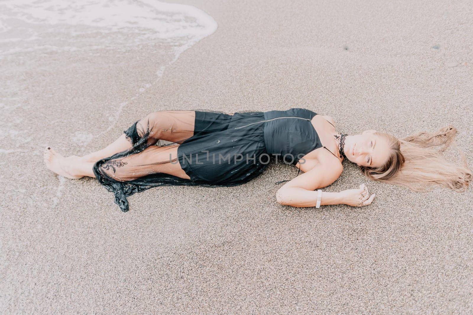 Woman summer travel sea. Happy tourist in black dress enjoy taking picture outdoors for memories. Woman traveler posing on sea beach surrounded by volcanic mountains, sharing travel adventure journey by panophotograph