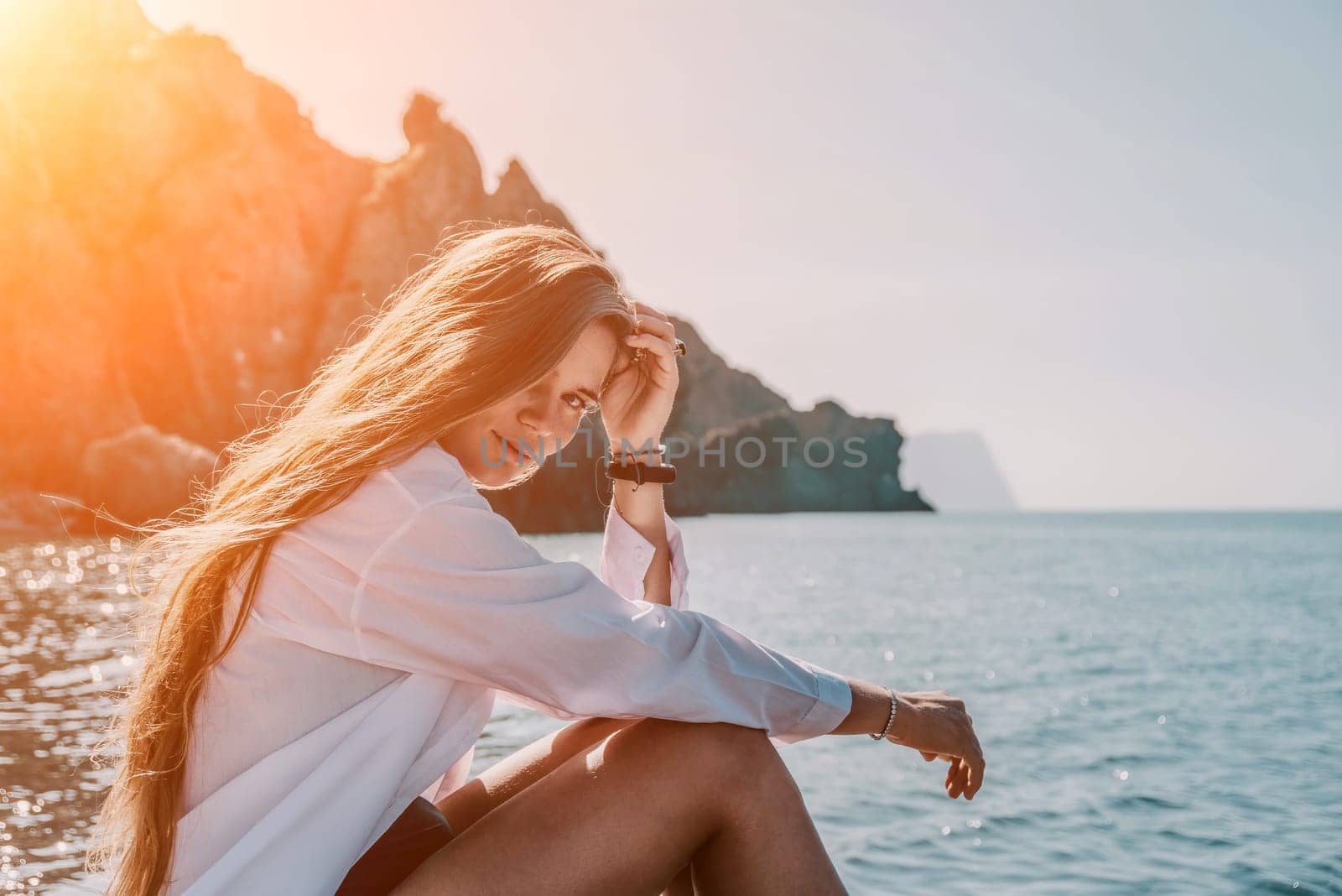 Young woman in black bikini and white shirt on Beach. Girl lying on pebble beach and enjoying sun. Happy lady in bathing suit chilling and sunbathing by turquoise sea ocean on hot summer day. Close up by panophotograph