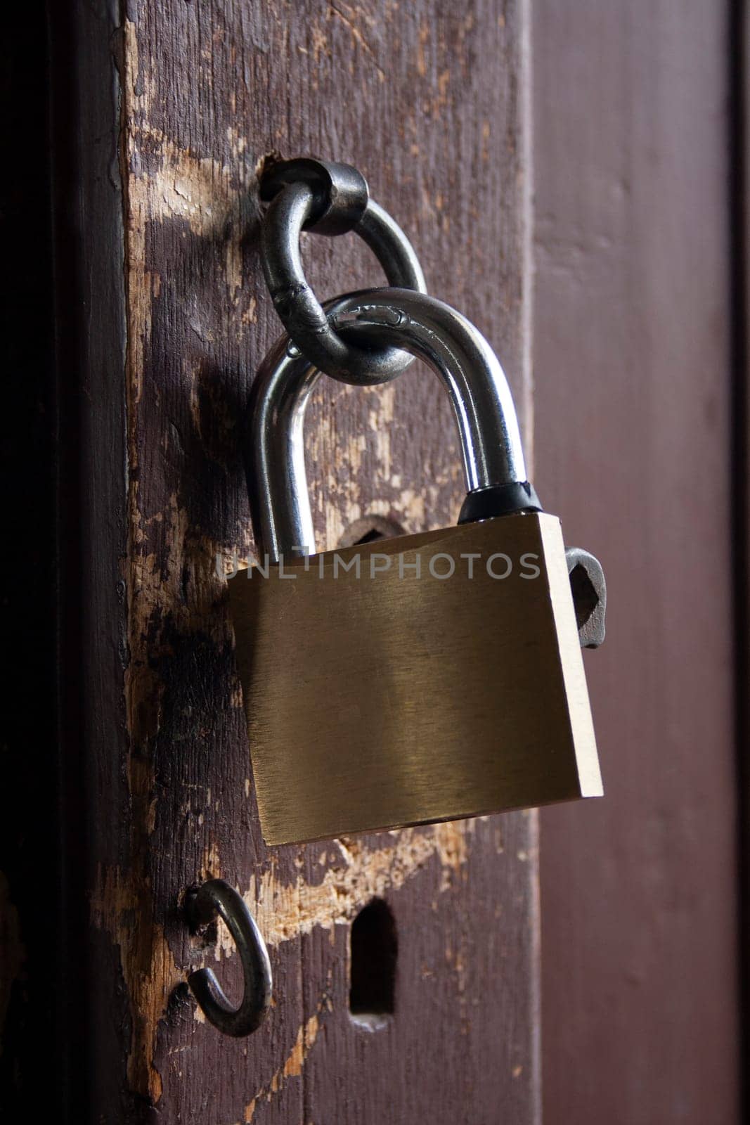 vertical photo of an iron padlock on an old worn wooden door. High quality photo