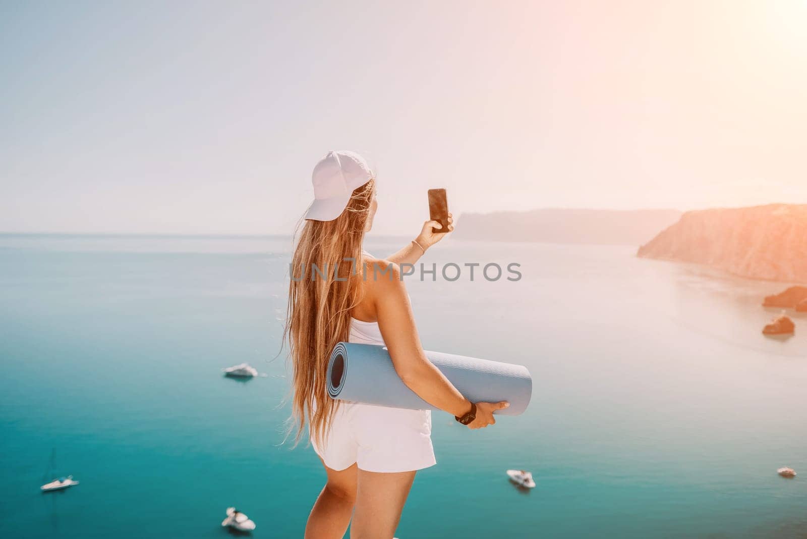 Young woman with black hair, fitness instructor in pink sports leggings and tops, doing pilates on yoga mat with magic pilates ring by the sea on the beach. Female fitness daily yoga concept