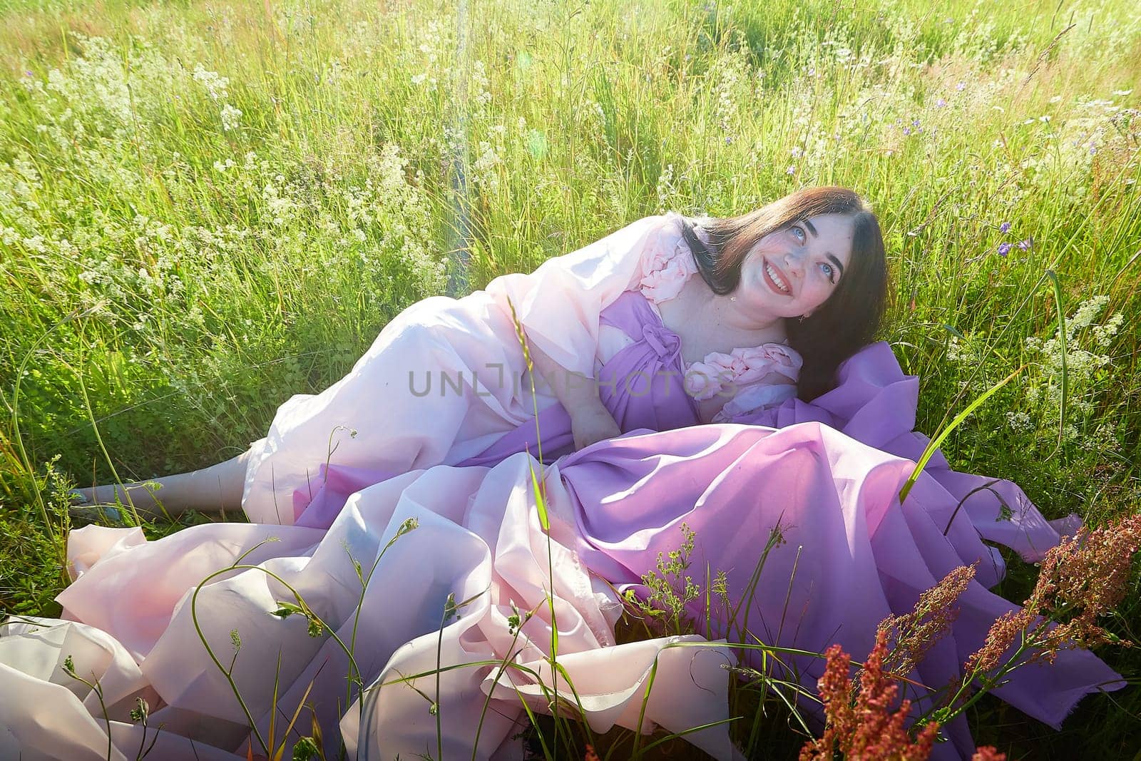 Young plump curvy beautiful teenage girl in a field or meadow on a sunny summer day in the evening sunset sun. Plump black-haired and black-eyed oriental model from the east fairy tale by keleny