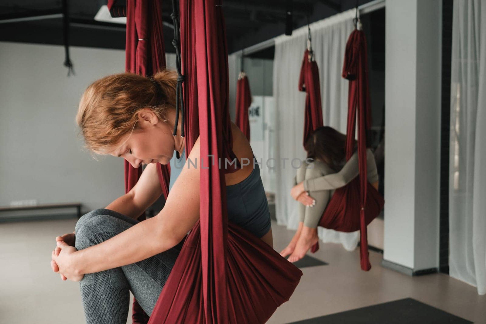 A group of women play sports on hanging hammocks. Fly yoga in the gym.