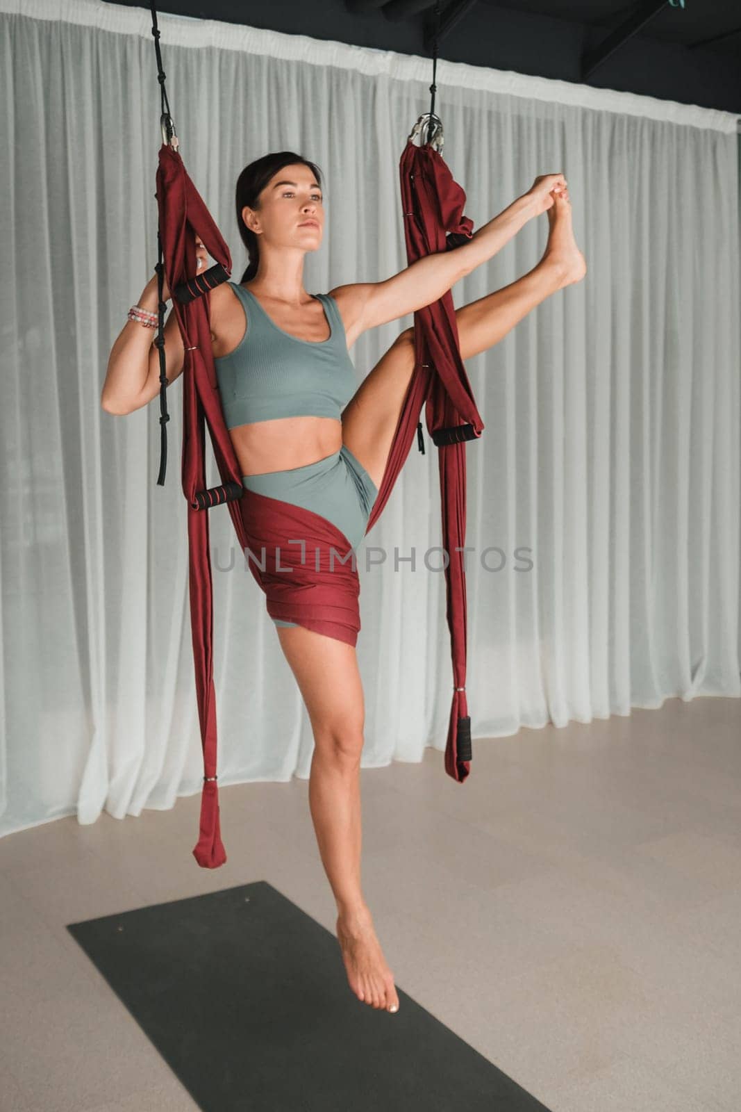 A girl does yoga in a hanging hammock in the gym. Fly yoga in the gym by Lobachad