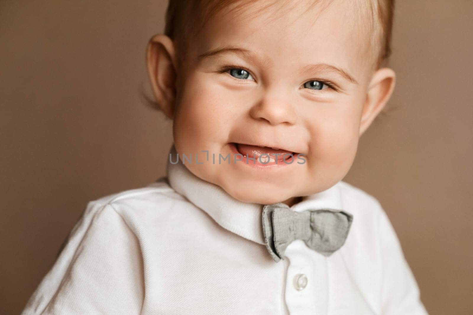 Portrait of a cheerful little boy in a white shirt with a bow tie.