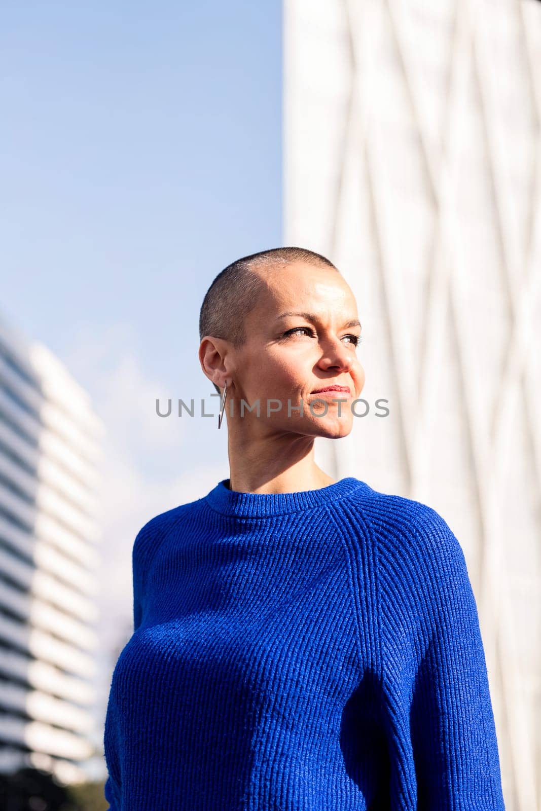 empowered woman with shaved head in cityscape, concept of urban lifestyle and rebel style, copy space for text