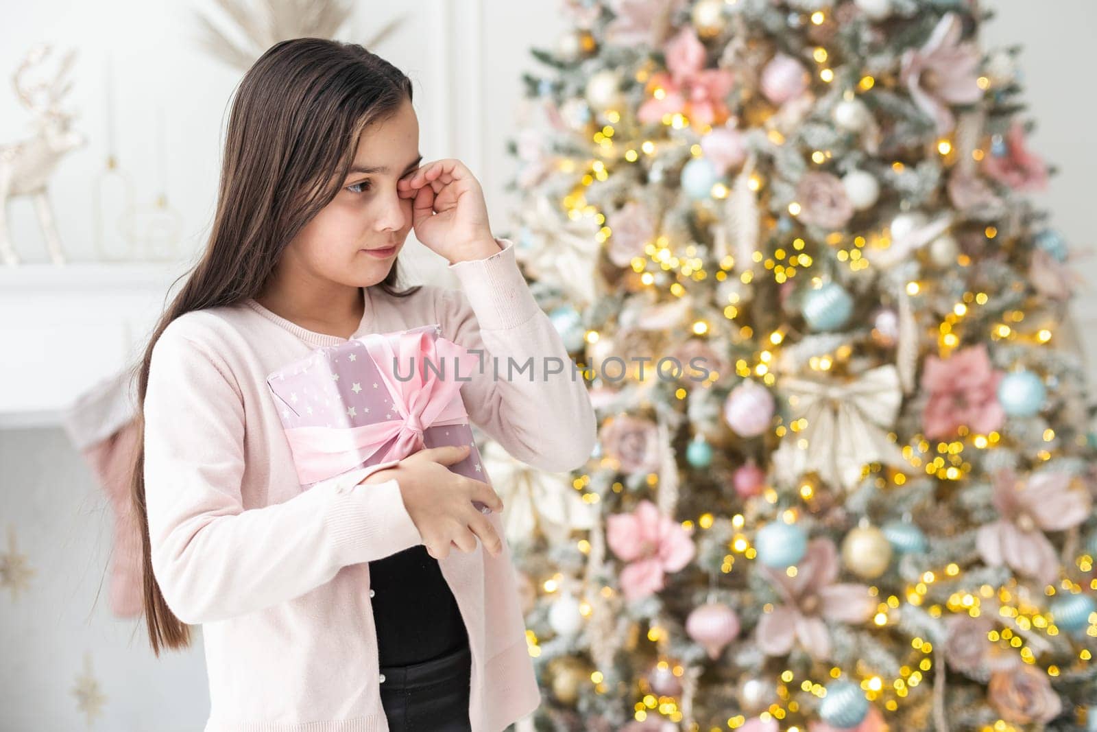 Cute little girl feeling unhappy with her Christmas gifts. living room on Xmas eve. by Andelov13