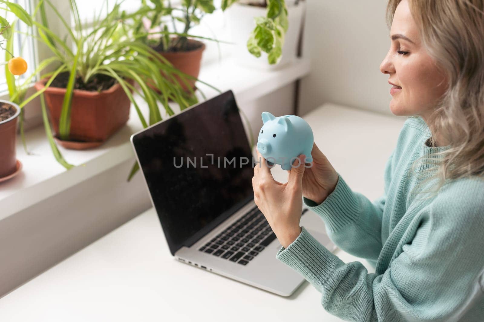 Young woman planning save salary money early years using laptop computer with pig bank save coin