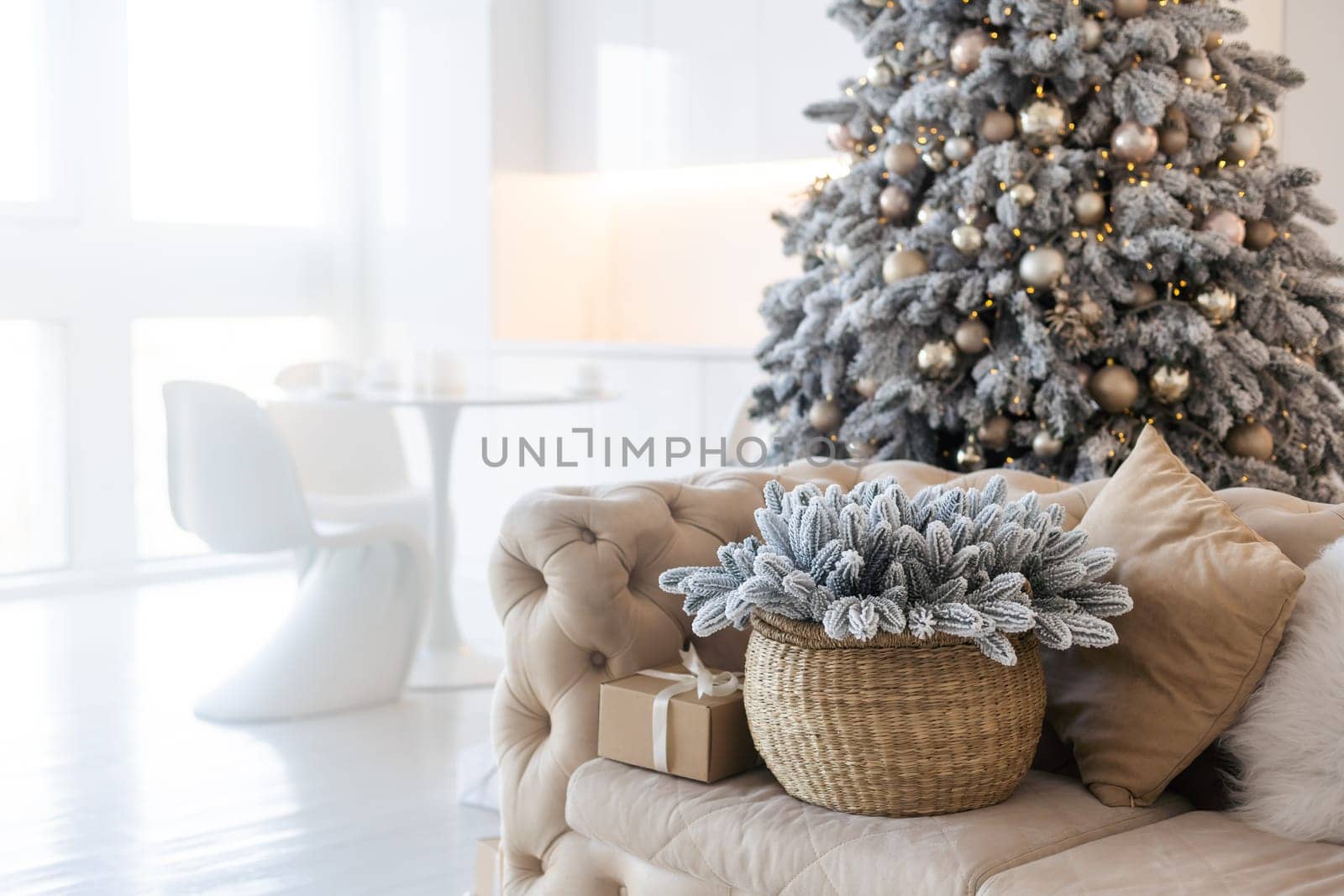 Classic white christmas interior with new year tree decorated. grey chair and presents under the tree.
