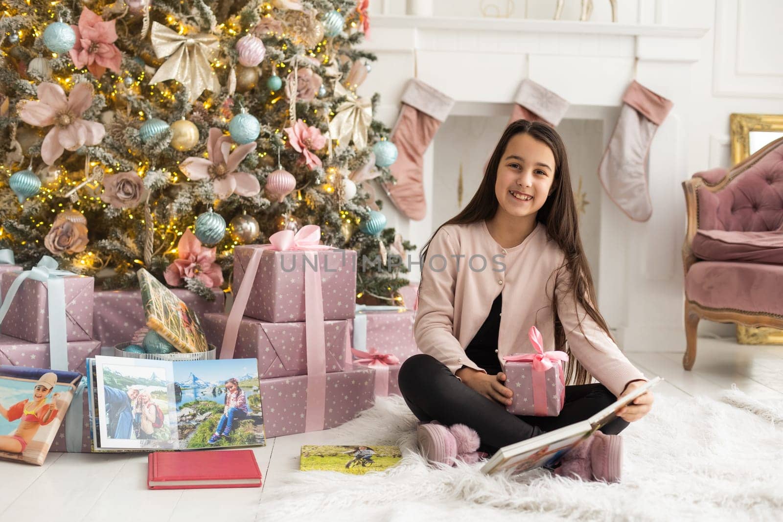 teenage girl looking at family photo album on Christmas morning. Cozy family moments at home.