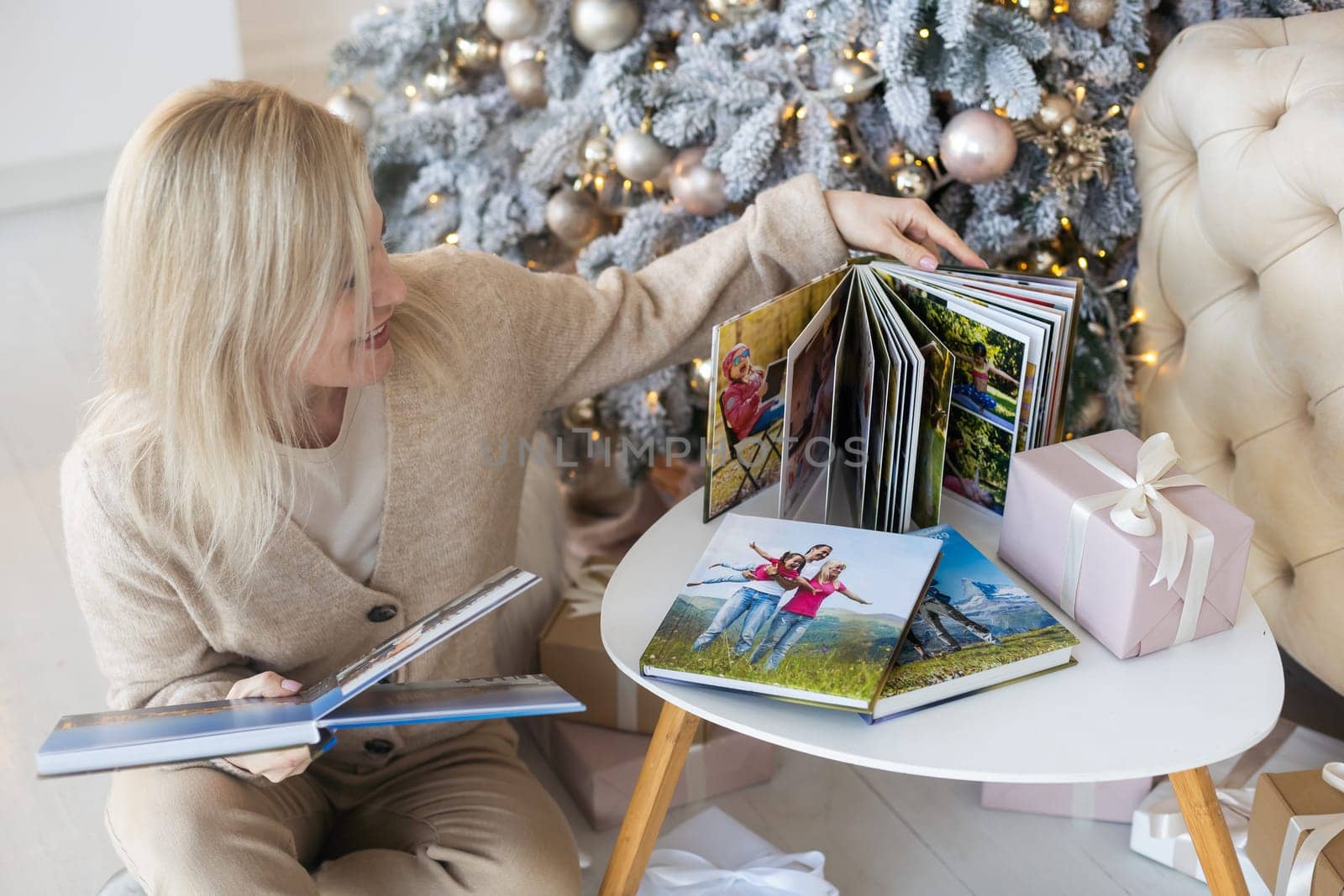 Beautiful young woman is looking her old photo album while spending Christmas alone at home by Andelov13