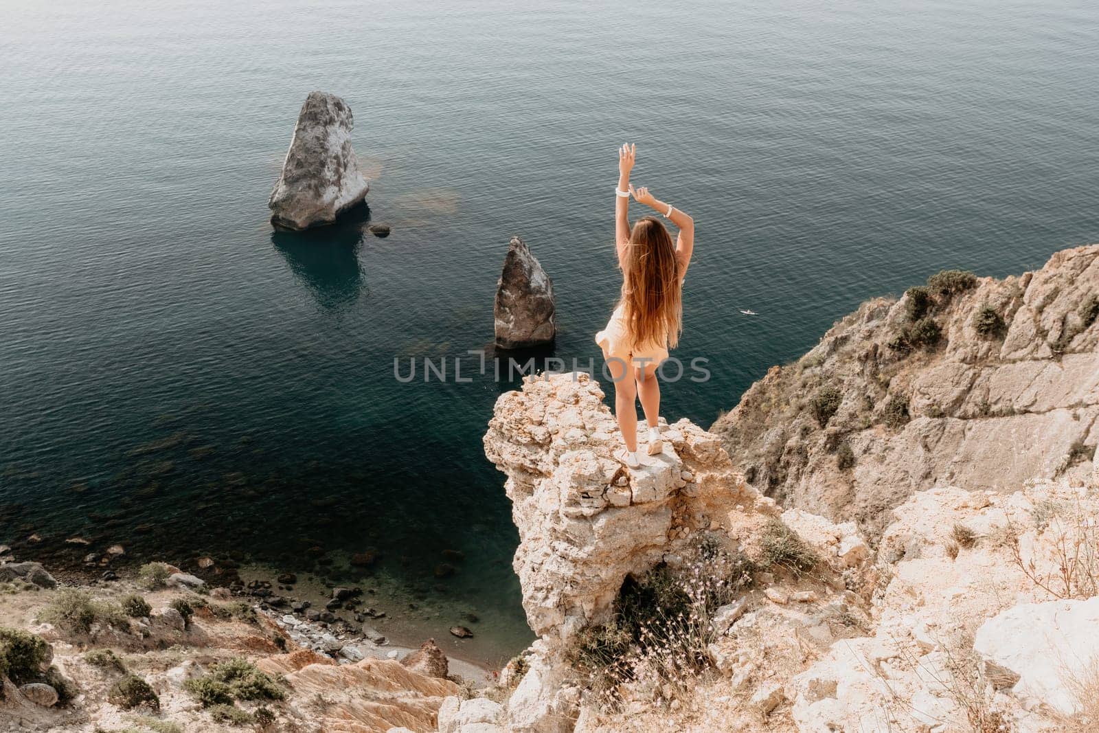 Woman travel sea. Happy tourist taking picture outdoors for memories. Woman traveler looks at the edge of the cliff on the sea bay of mountains, sharing travel adventure journey.