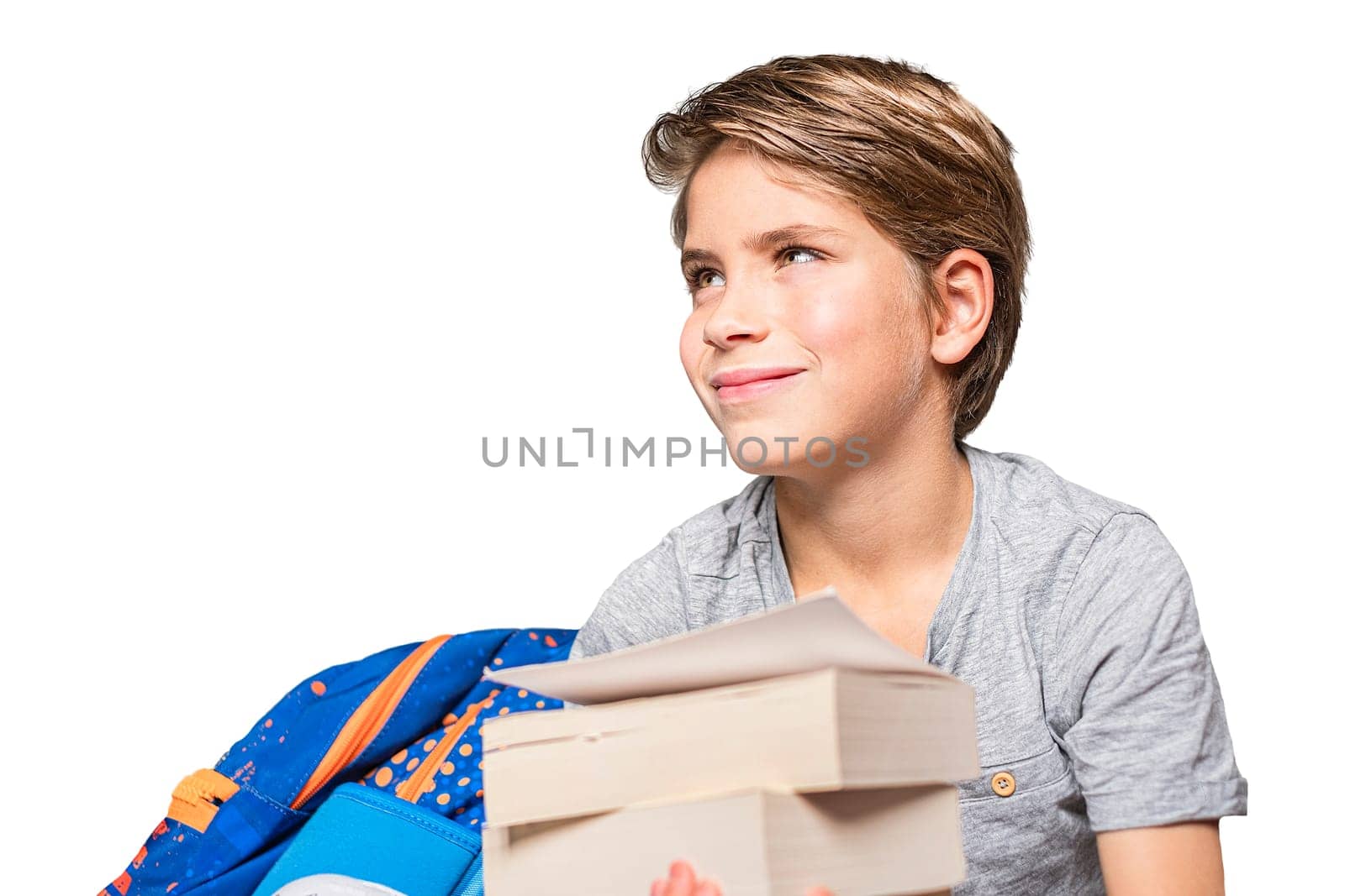 Portrait of schoolboy with school bag and books. Teenager smiling and looking away. Happy teen boy, isolated on white background.