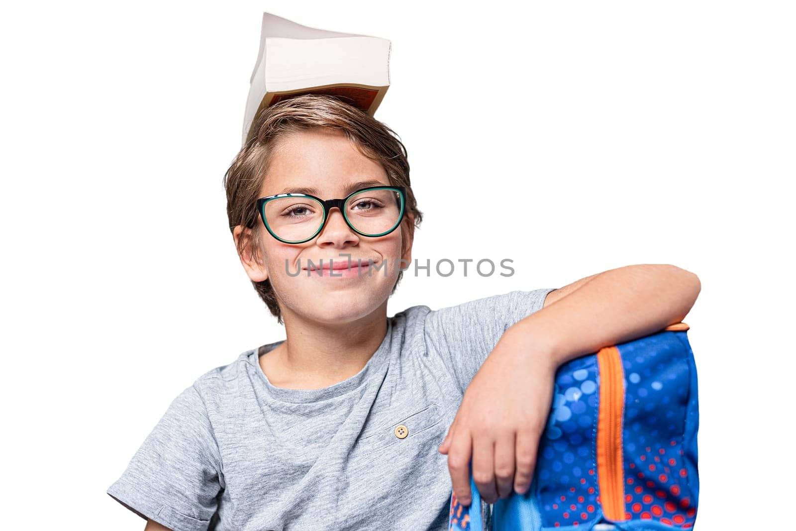 Portrait of schoolboy with school bag and book on head Teenager smiling with glasses and looking at camera. Happy teen boy, isolated on white background