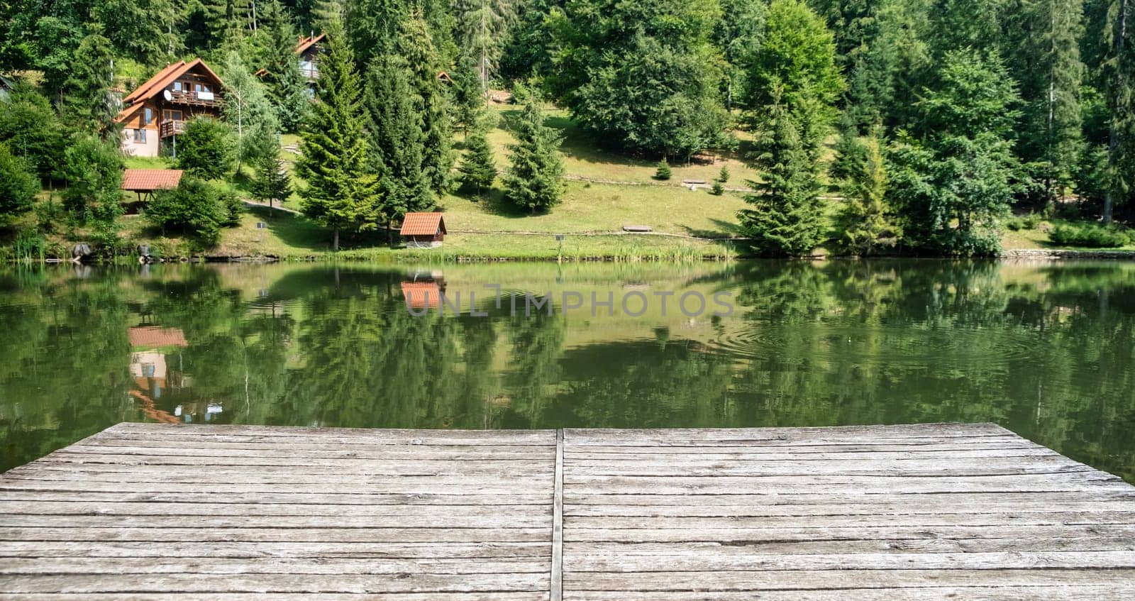 Wooden board, empty in front of blurred lake and house in forest. Perspective brown wood over blur in outdoor - can be used for display or montage your products.Mock up for display of product. by igor010