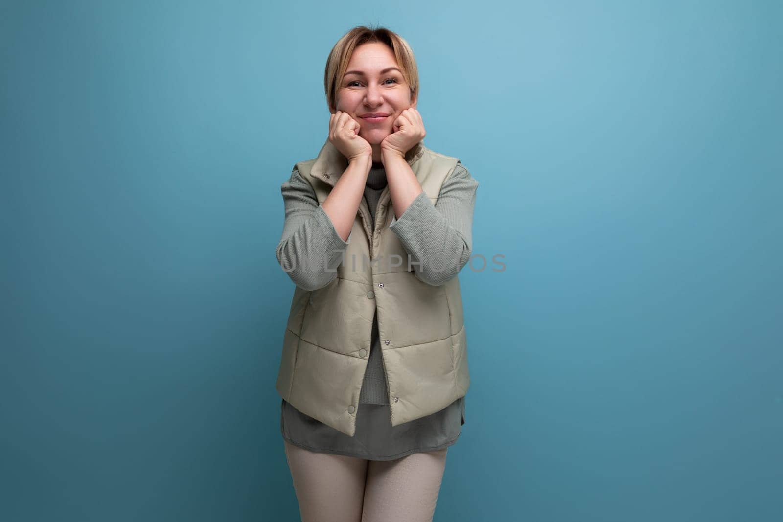 portrait of a positive caucasian blond young woman in a spring look with a smile on a studio background.