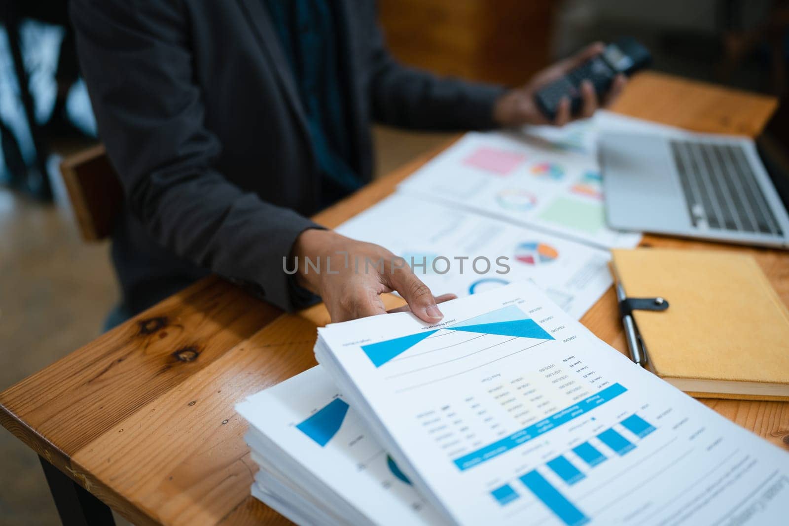 businessman or accountant working on calculator and laptop computer to calculate business data during using accountancy document at office