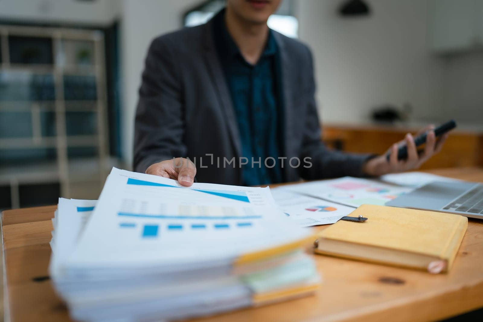 businessman or accountant working on calculator and laptop computer to calculate business data during using accountancy document at office
