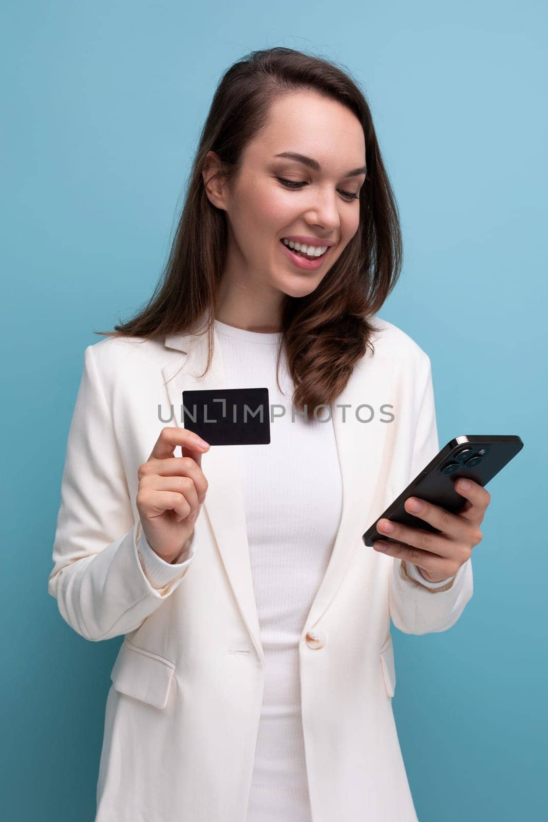 brunette woman in a dress uses electronic money transfer using a card and a smartphone.