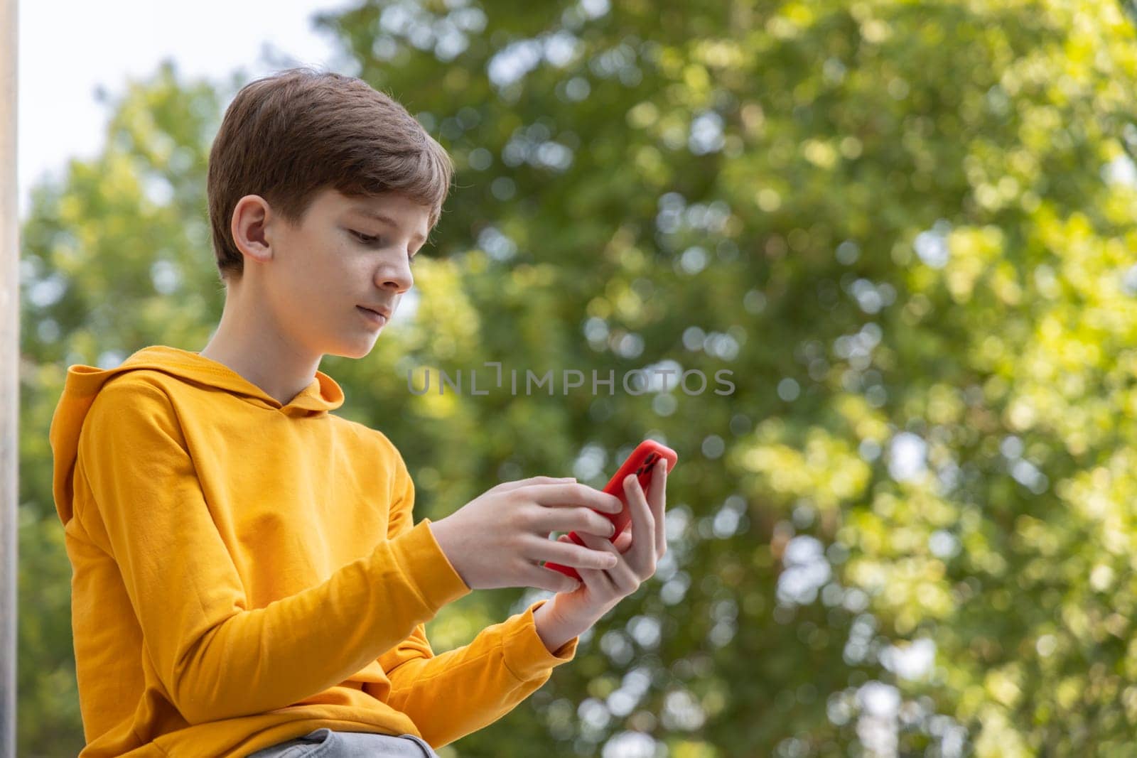 Streetstyle photo of young boy using smartphone. Communication on the go. Playing games. Gaming after school