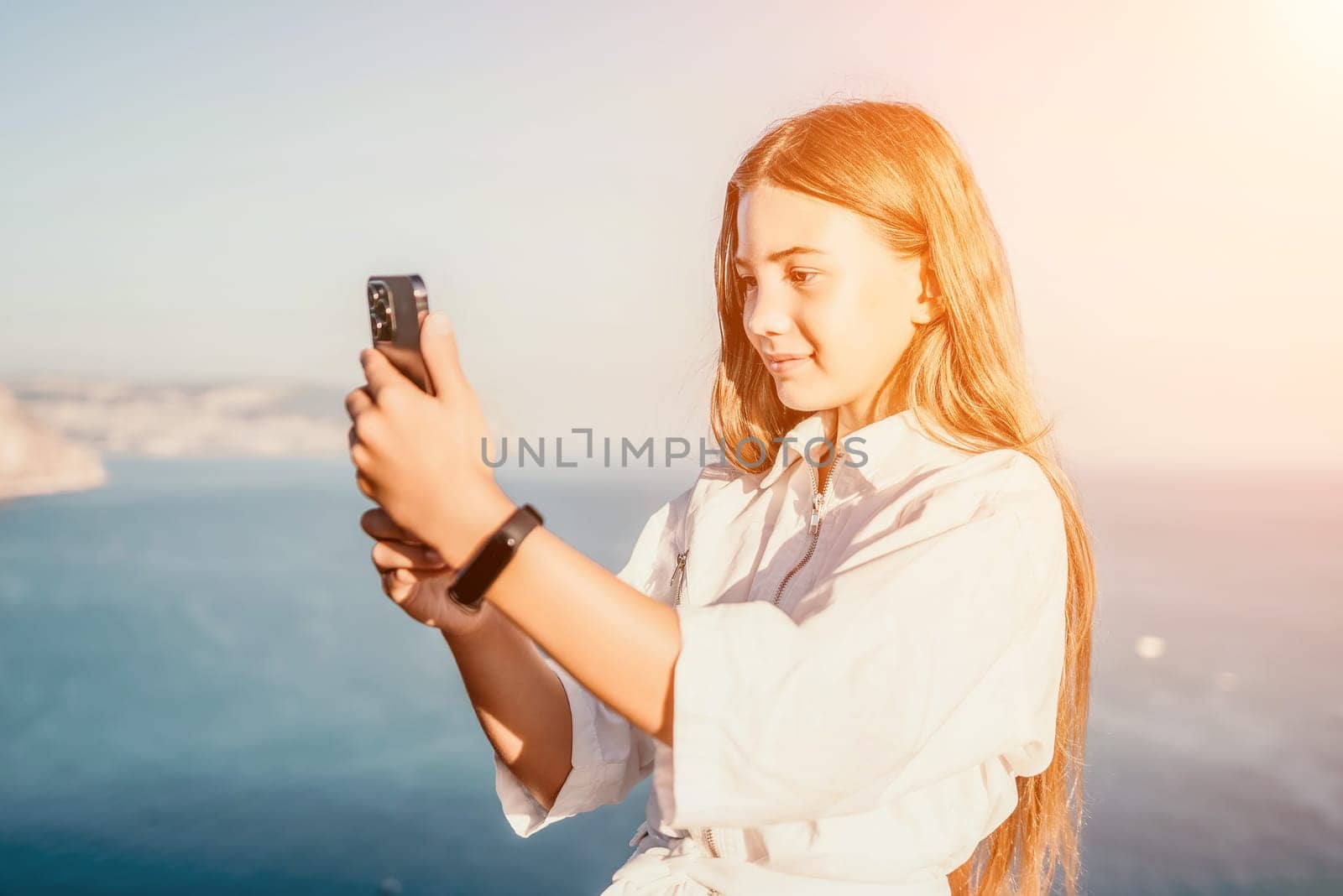 Brown-haired young romantic teenager girl corrects long hair on beach at summer evening wind