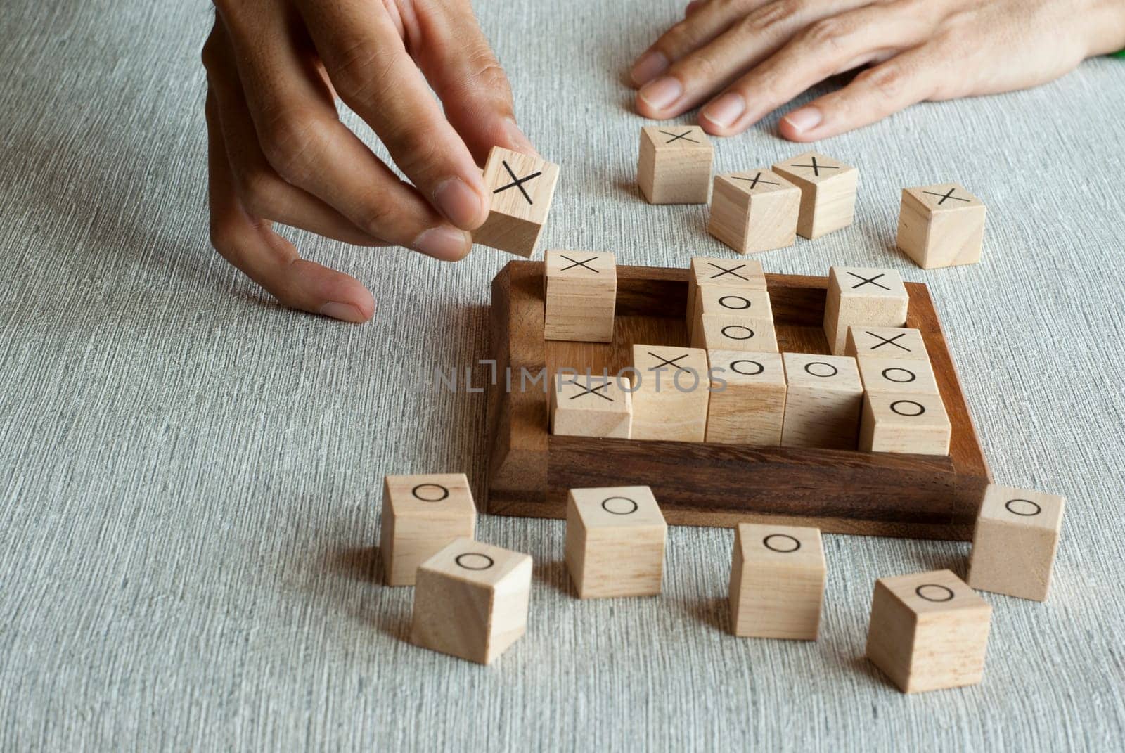 Tic tac toe OX game made of wooden blocks with hand player