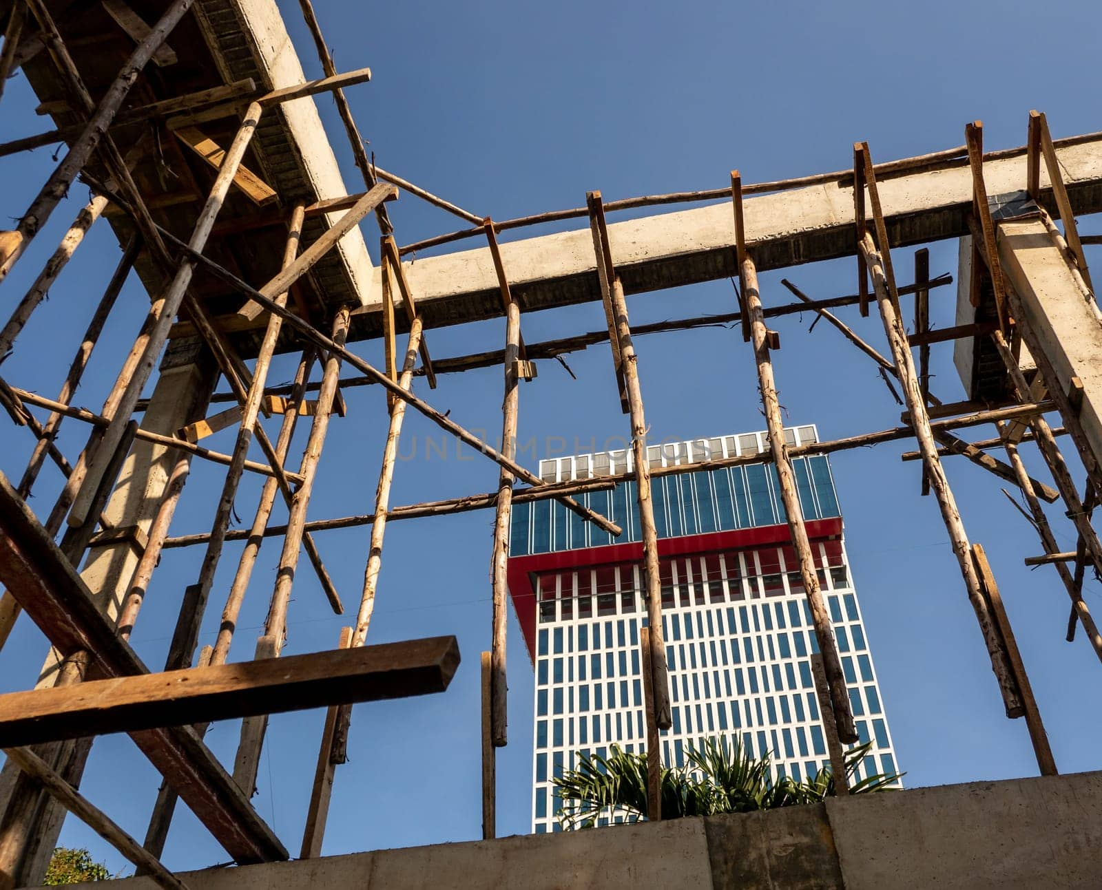 Temporary wooden pole for supports the concrete structure a building under construction by Satakorn