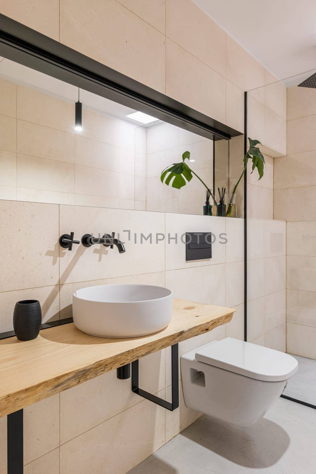Light style bathroom with a toilet bowl, big mirrors and a sink and a glass shower cabin. The concept of a stylish but simple renovation in a new building.