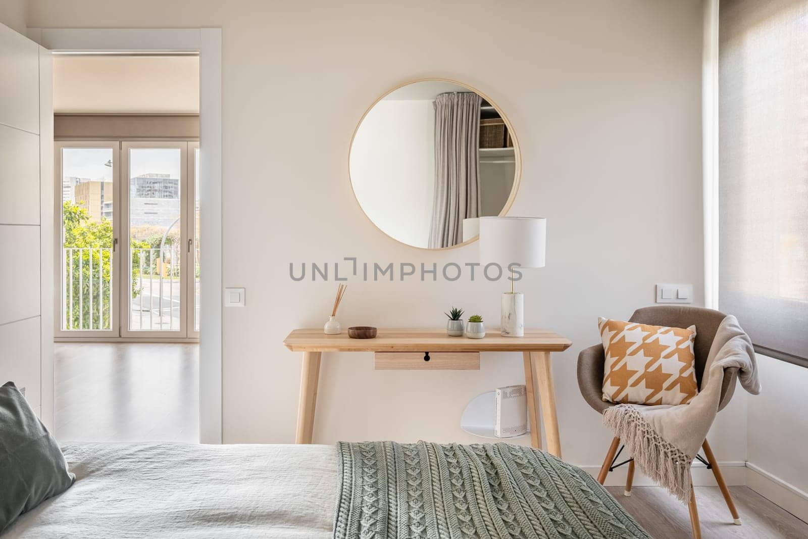Bedroom in light colors with wooden eco furniture and accessories with a mirror and a panoramic window. The concept of a laconic Scandinavian interior. Copyspace.