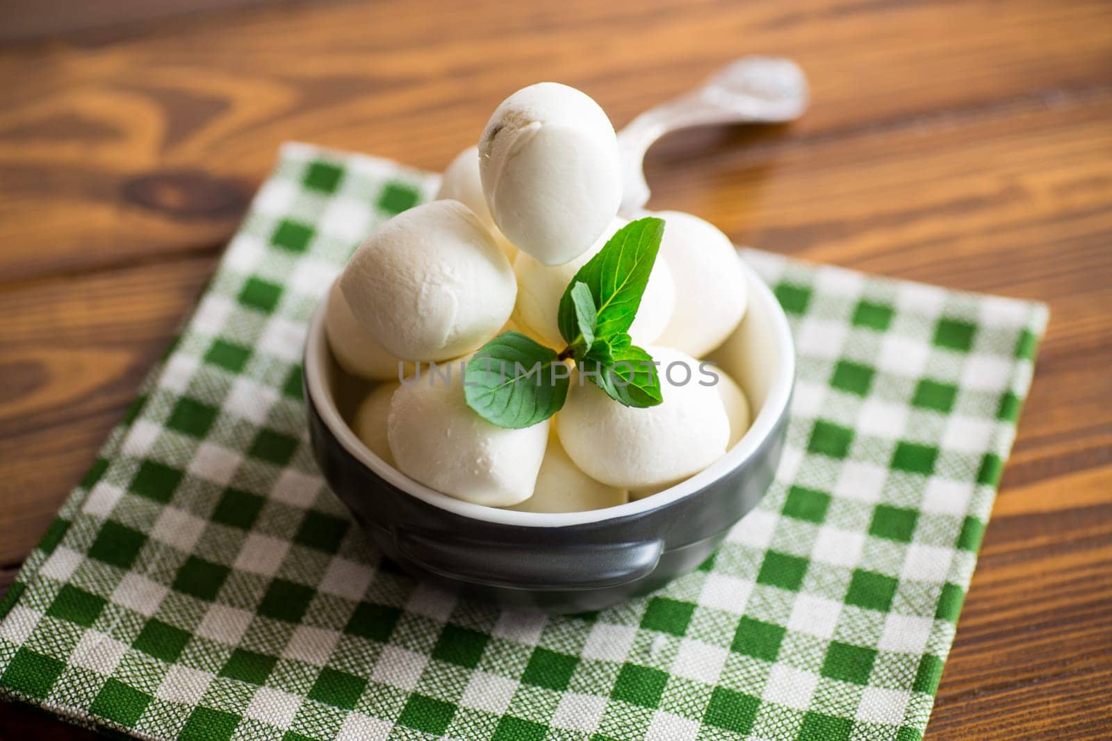 Small balls of traditional mozzarella in a ceramic bowl with mint