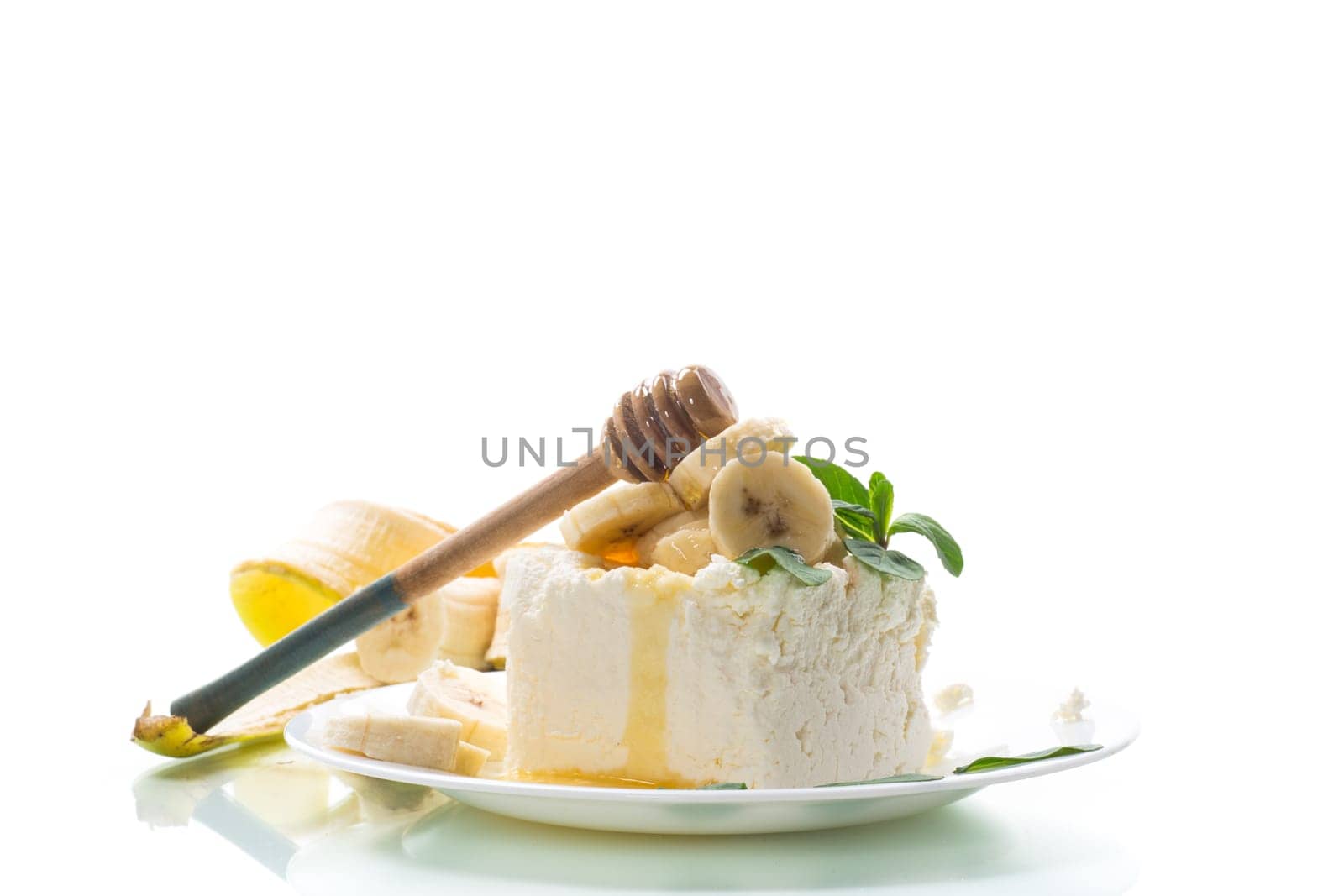Portion of homemade milk curd with banana slices and honey, isolated on white background.