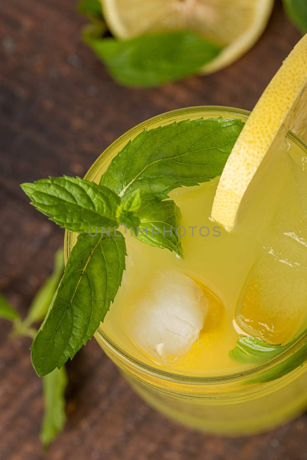 Lemonade with fresh mint leaves and lemon slice in glass glass on wooden table by Sonat