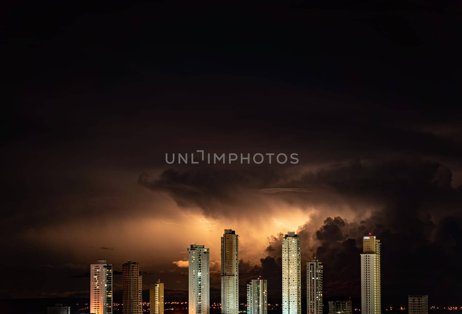 Spectacular high-rise buildings in the cityscape are illuminated by lightning strikes during a dark and stormy night. Plenty of negative space for text.