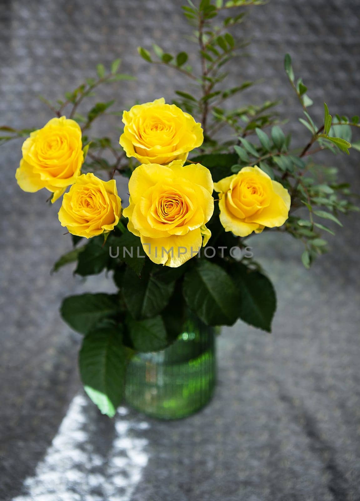Beautiful yellow roses in a green vase stand on a blanket. Surprise and holiday concept. by sfinks