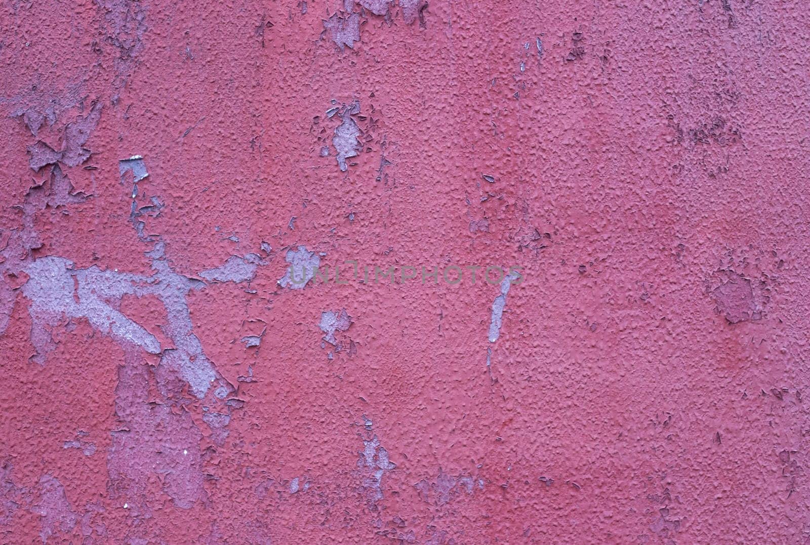 An old shabby wall with time-damaged red paint.