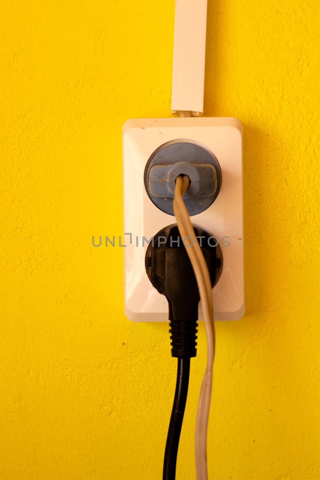 Double white socket on a yellow wall. Electric wires. Old wiring. Old plugs.