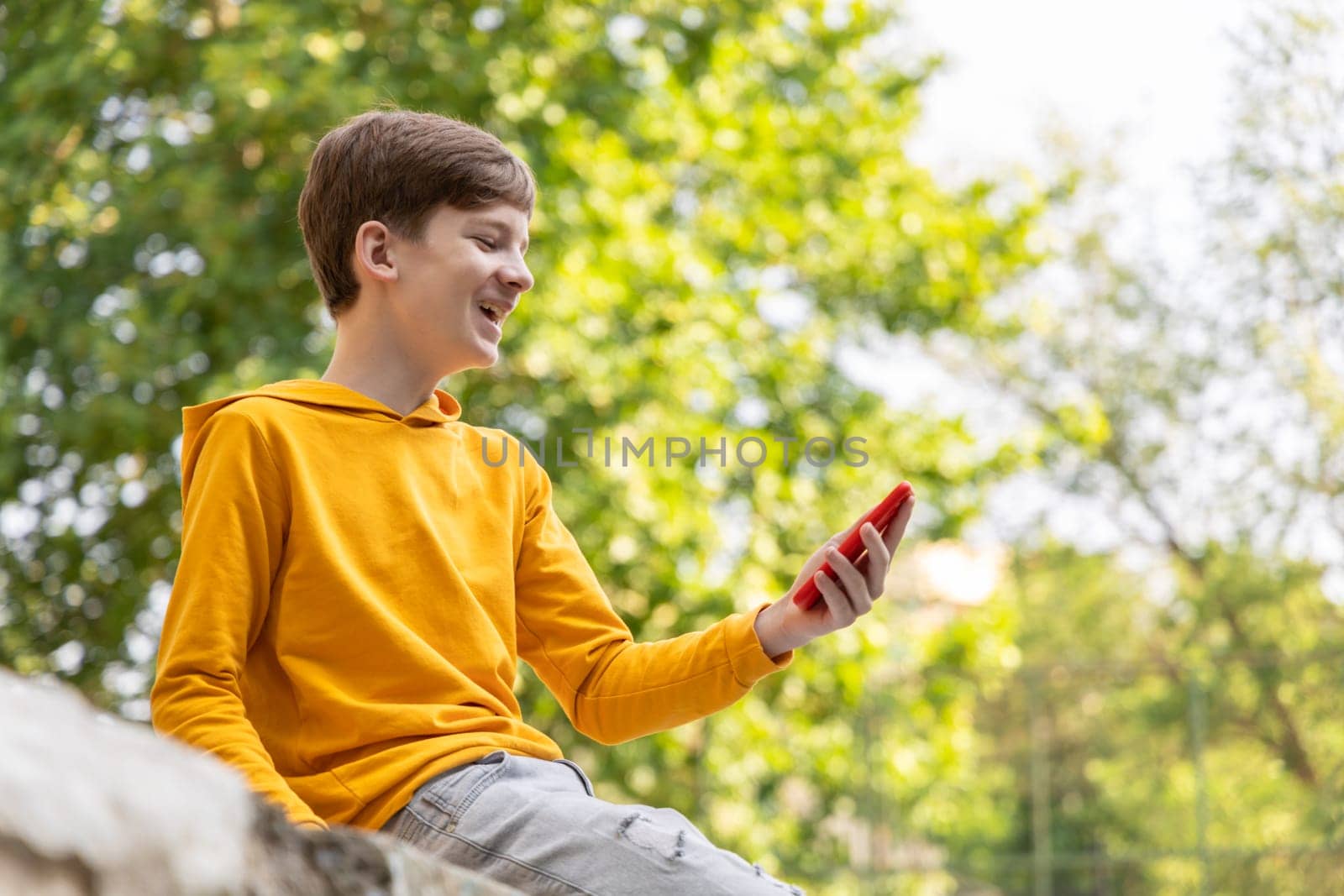 Happy smiling teen boy talking on video call using phone outside