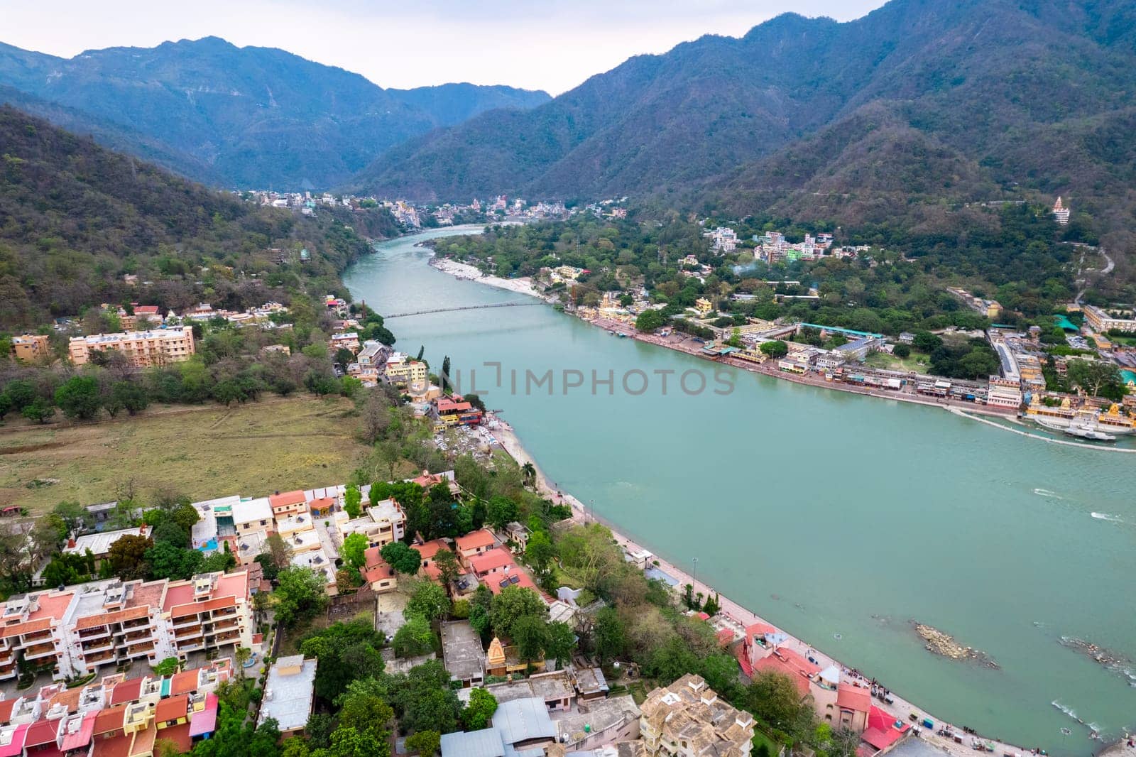 aerial drone shot over ram setu jhula suspension bridge with temples on the bank of river ganga in the holy spiritual city of Rishikesh Haridwar uttarakhand india