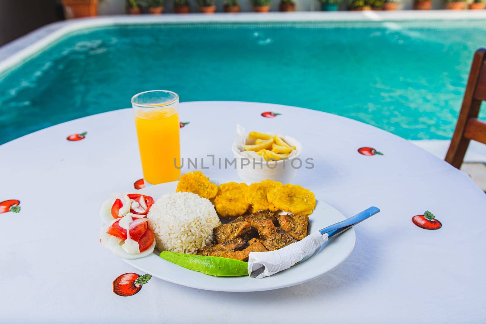 Delicious breakfast near a crystal clear pool. Traditional breakfast with orange juice served near a swimming pool by isaiphoto