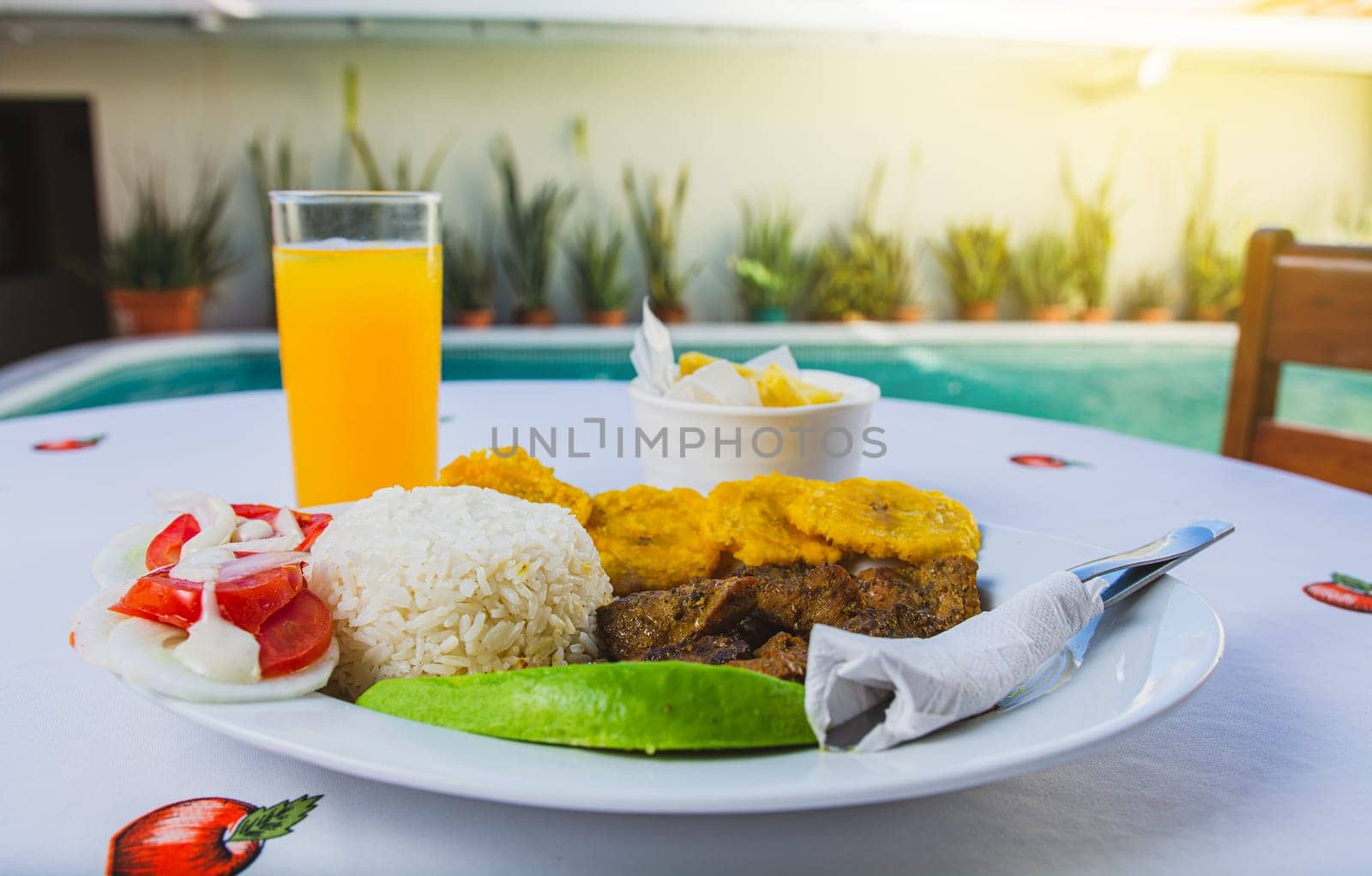 Traditional breakfast with orange juice near a swimming pool. Vacation breakfast near a swimming pool, Delicious breakfast near a crystal clear pool