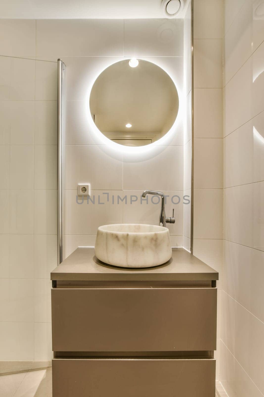 a bathroom with a sink and mirror on the wall next to it is an illuminated round light above the sink